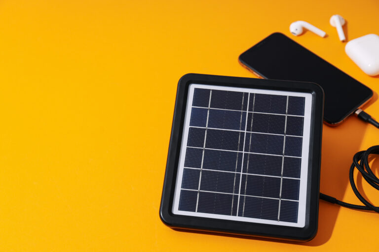 Solar panel, smartphone and headphones on orange background, spa
